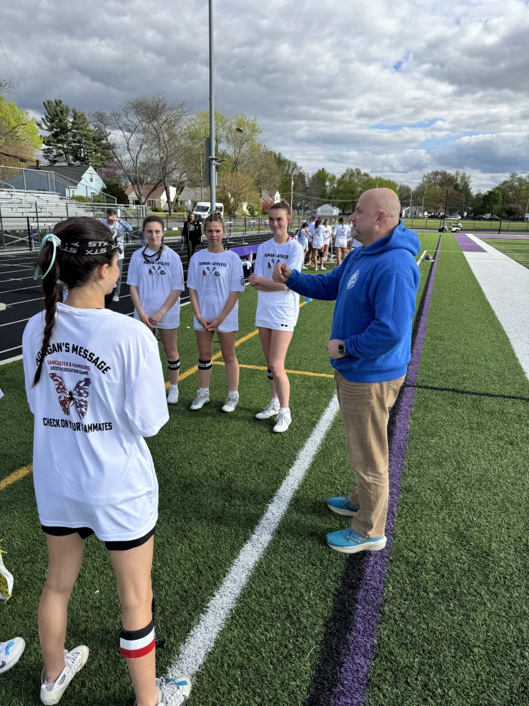 Bryan from Roofs by Bryan speaking with a girls lacrosse team on a field during a community event
