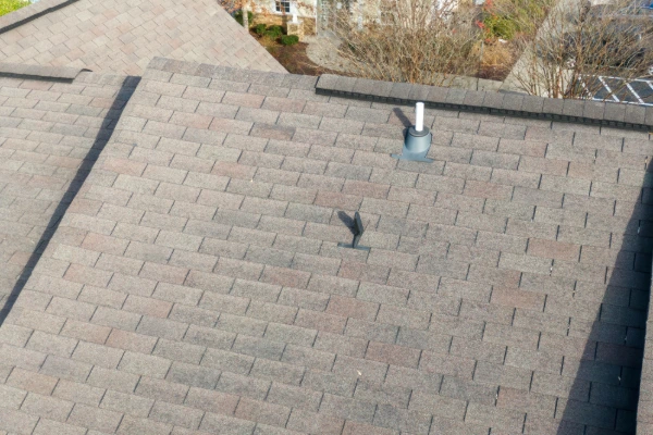 Aerial view of a worn asphalt shingle roof nearing the end of its serviceable life, showing discoloration and damage.