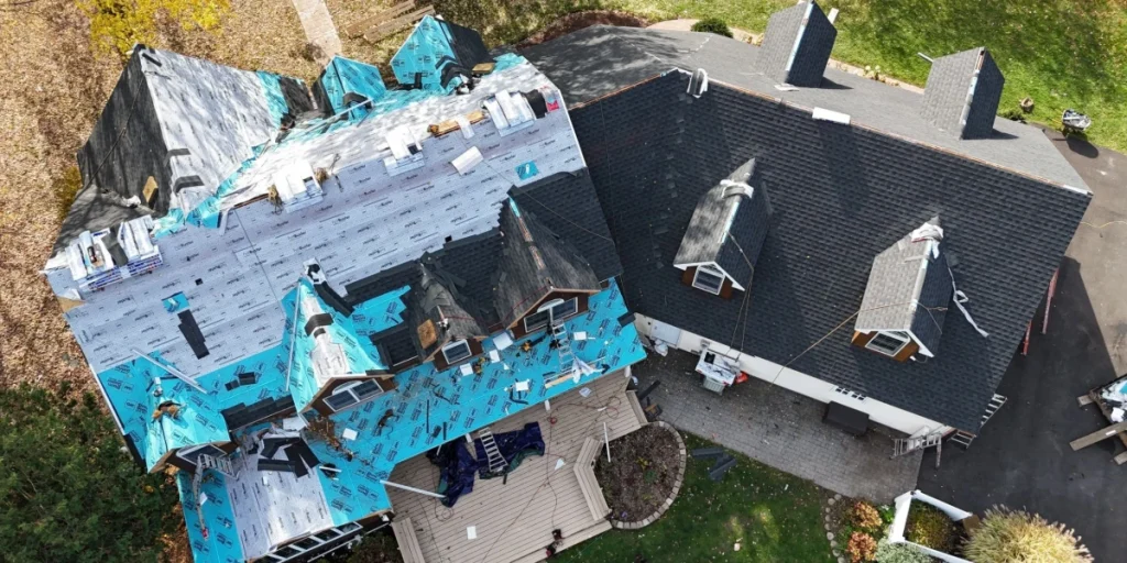 Aerial view of a Hamburg NY home mid-roof replacement, showing new underlayment and shingle bundles staged across the deck