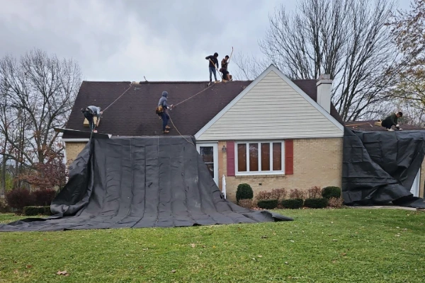 Roofing crew using large tarps to protect the lawn and landscaping during a residential roof replacement in the Hamburg NY area