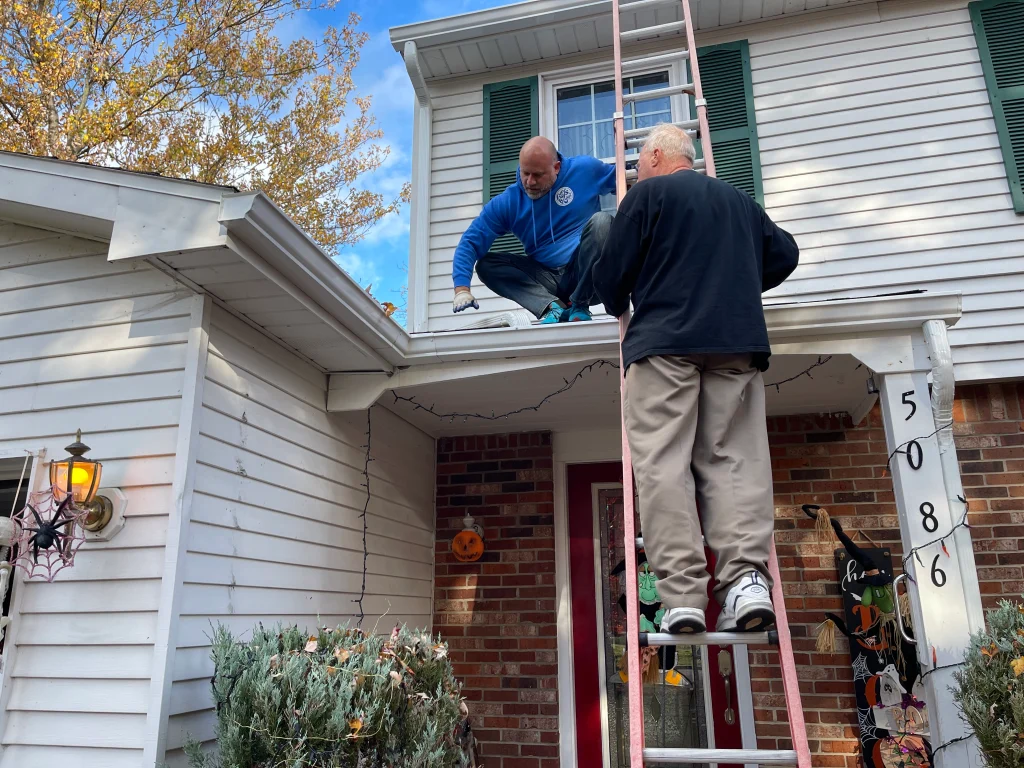 Bryan on a porch roof showing a customer the issue with the roof.