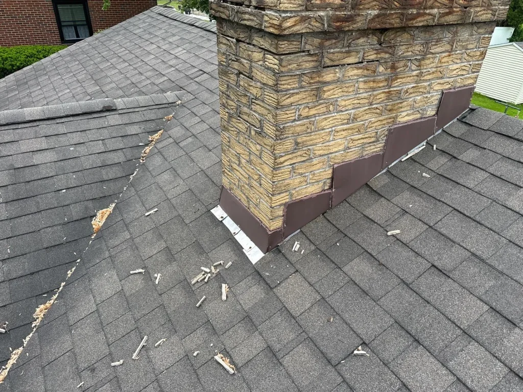 Existing chimney flashing and asphalt shingles inspected during the Angola, NY roofing project
